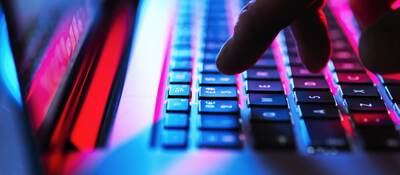 Man typing at his laptop computer at night.